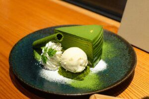 Green matcha slice of cake with vanilla ice cream scoop